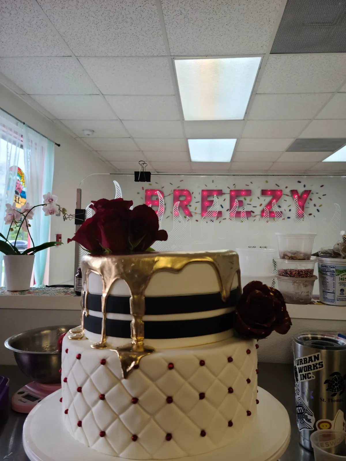 Two-tier custom cake with quilted white fondant, a gold drip and dark red roses